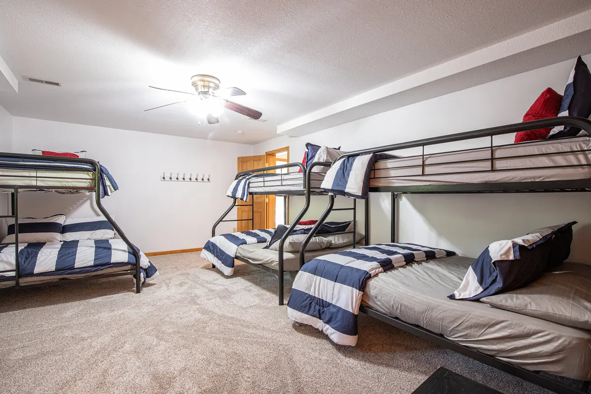 A playful kids' or teen zone with bunk beds, a ceiling fan, and a carpeted floor. The area feels relaxed and fun, ideal for sleepovers, reading, or playing games—a perfect retreat for younger guests.