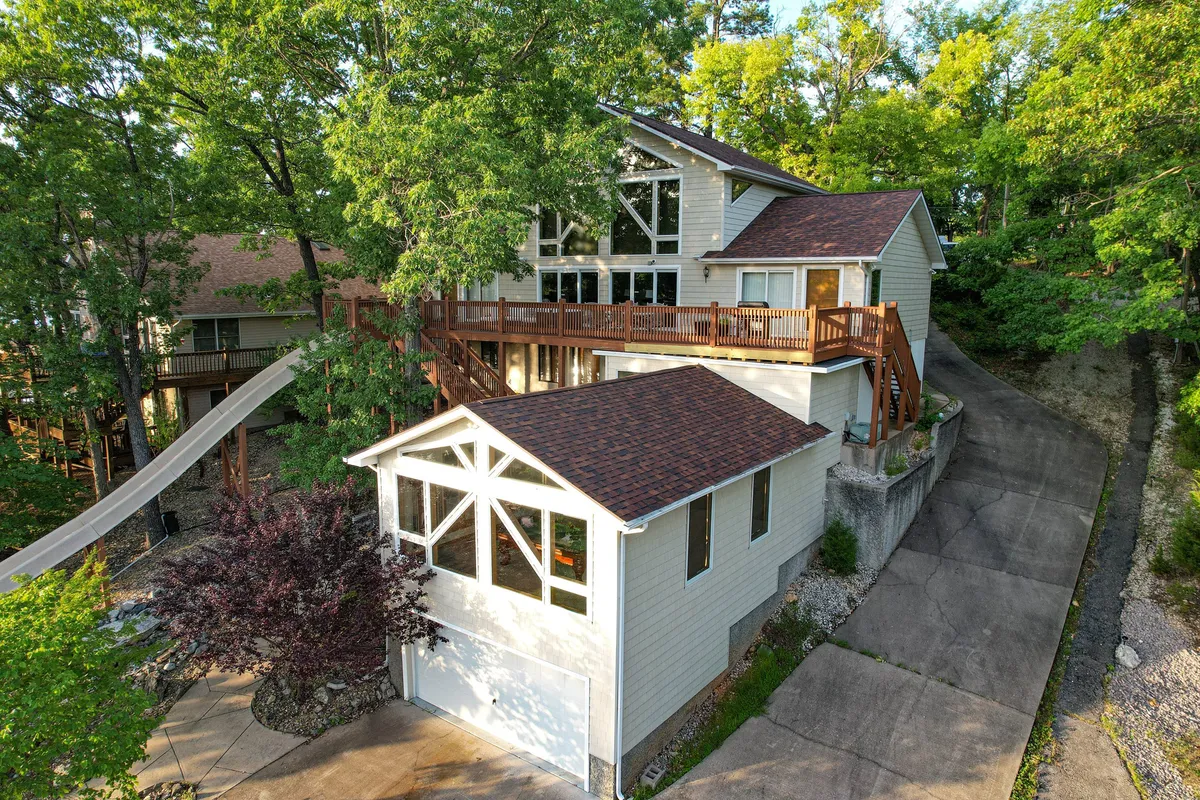 A wide view of the home's large deck, expansive windows, and surrounding trees, with a clear sense of space for outdoor gatherings and family games. The atmosphere is both welcoming and versatile, providing ample room for group activities and celebrations.